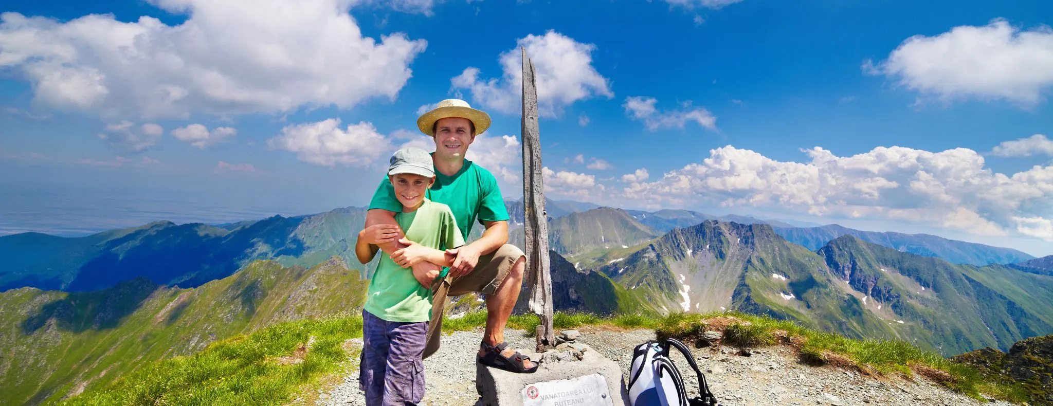 Happy father and son on the Buteanu peak in Romanian Carpathians, the inscriptions reads "Peak Buteanu, 2507 m"